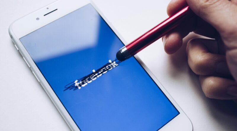 Close-up of a smartphone with a stylus crossing out text on its screen.