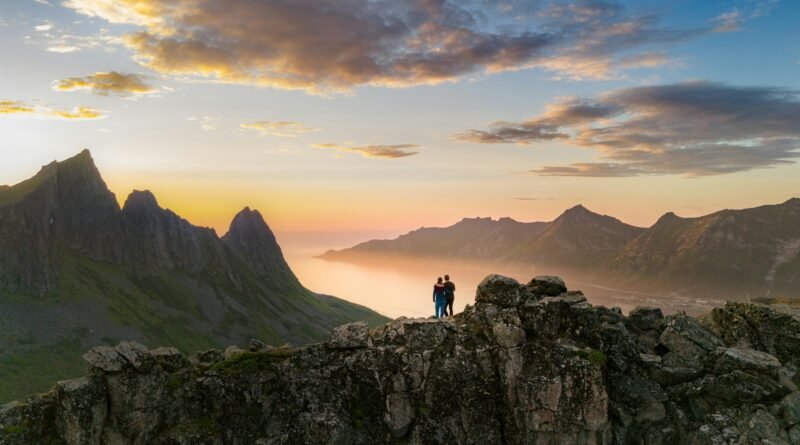Couple admiring the stunning sunset view over the mountains in Senja, Norway.