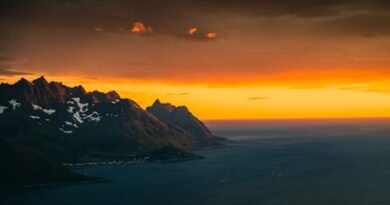 Stunning coastal view of Troms og Finnmark, Norway with a vivid sunset sky.