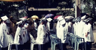 Group of children in academic gowns celebrating graduation outdoors.