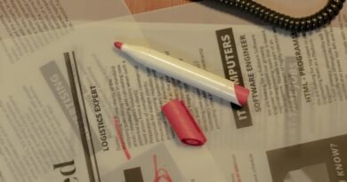 Close-up of a job search scene with a newspaper, red marker, and telephone, indicating job hunting.